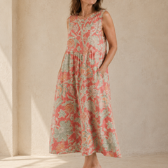 Beth - Robe Midi Florale in een luxe studiosetting met warme kalkstenen achtergrond, met koraalroze linnen, zachte saliegroene bloemenprint, ronde hals, midi lengte en vloeiende A-lijn snit.