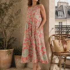 Beth - Robe Midi Florale gestyled met leren platte sandalen en een geweven tas, een elegante mouwloze midi jurk in koraalroze linnen met florale print en ontspannen Franse uitstraling.
