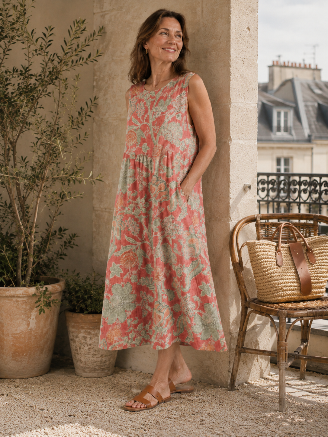 Beth - Robe Midi Florale gestyled met leren platte sandalen en een geweven tas, een elegante mouwloze midi jurk in koraalroze linnen met florale print en ontspannen Franse uitstraling.
