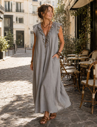 Camélia - Robe Longue Bohème gedragen in een Parijse lifestyle setting, een lange bohemian jurk in steengrijze taupe gewassen stof met diepe V-hals, rucheafwerking, zachte kapmouwtjes en zijzakken.