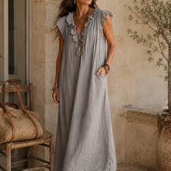Camélia - Robe Longue Bohème gestyled met bruine leren sandalen en een geweven tas, een elegante bohemian maxi jurk in steengrijze taupe stof met diepe V-hals, ruches en ontspannen Franse uitstraling.