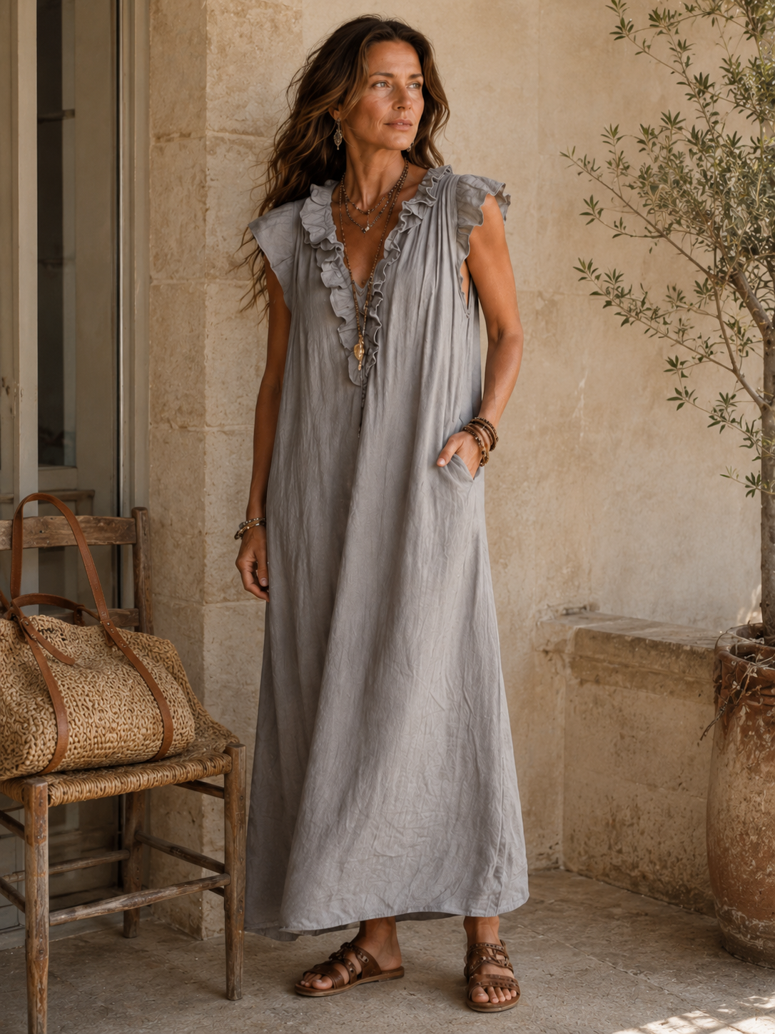Camélia - Robe Longue Bohème gestyled met bruine leren sandalen en een geweven tas, een elegante bohemian maxi jurk in steengrijze taupe stof met diepe V-hals, ruches en ontspannen Franse uitstraling.