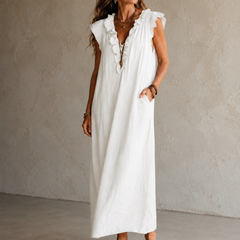 Camélia - Robe Longue Bohème in een luxe studiosetting met warme kalkstenen achtergrond, uitgevoerd in steengrijze taupe stof met gekreukte textuur, diepe V-hals met ruches en een vloeiende maxi pasvorm.