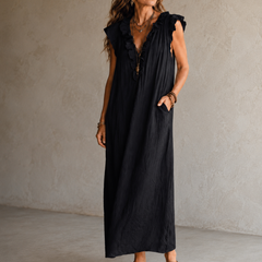 Camélia - Robe Longue Bohème in een luxe studiosetting met warme kalkstenen achtergrond, uitgevoerd in steengrijze taupe stof met gekreukte textuur, diepe V-hals met ruches en een vloeiende maxi pasvorm.
