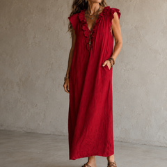 Camélia - Robe Longue Bohème in een luxe studiosetting met warme kalkstenen achtergrond, uitgevoerd in steengrijze taupe stof met gekreukte textuur, diepe V-hals met ruches en een vloeiende maxi pasvorm.