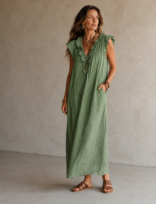 Camélia - Robe Longue Bohème in een luxe studiosetting met warme kalkstenen achtergrond, uitgevoerd in steengrijze taupe stof met gekreukte textuur, diepe V-hals met ruches en een vloeiende maxi pasvorm.